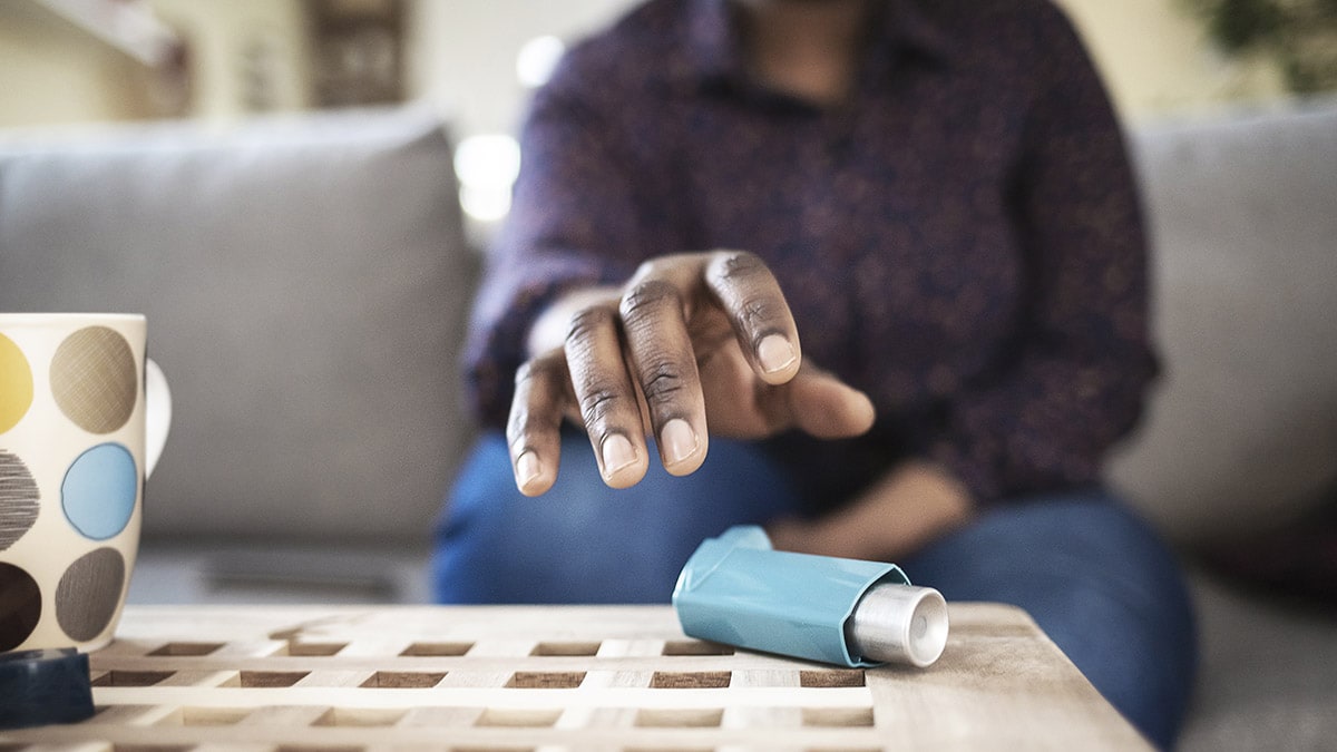 Woman reaching for inhaler on her coffee table.