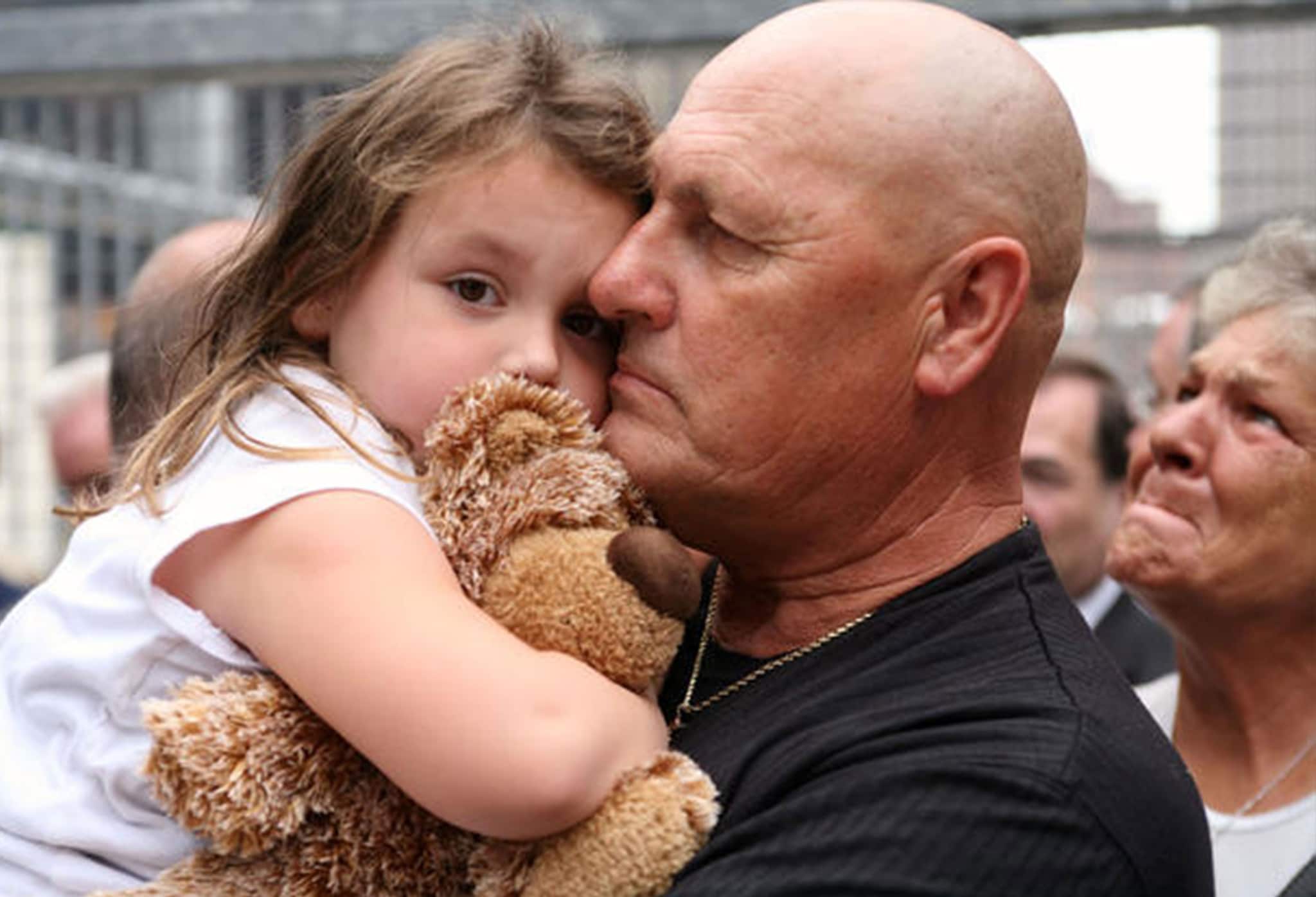 A man holding a young girl and stuffed animal at a rally.