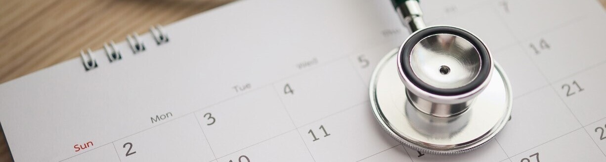 A stethoscope rests on a calendar. Photo credit: Getty/Kwangmooza