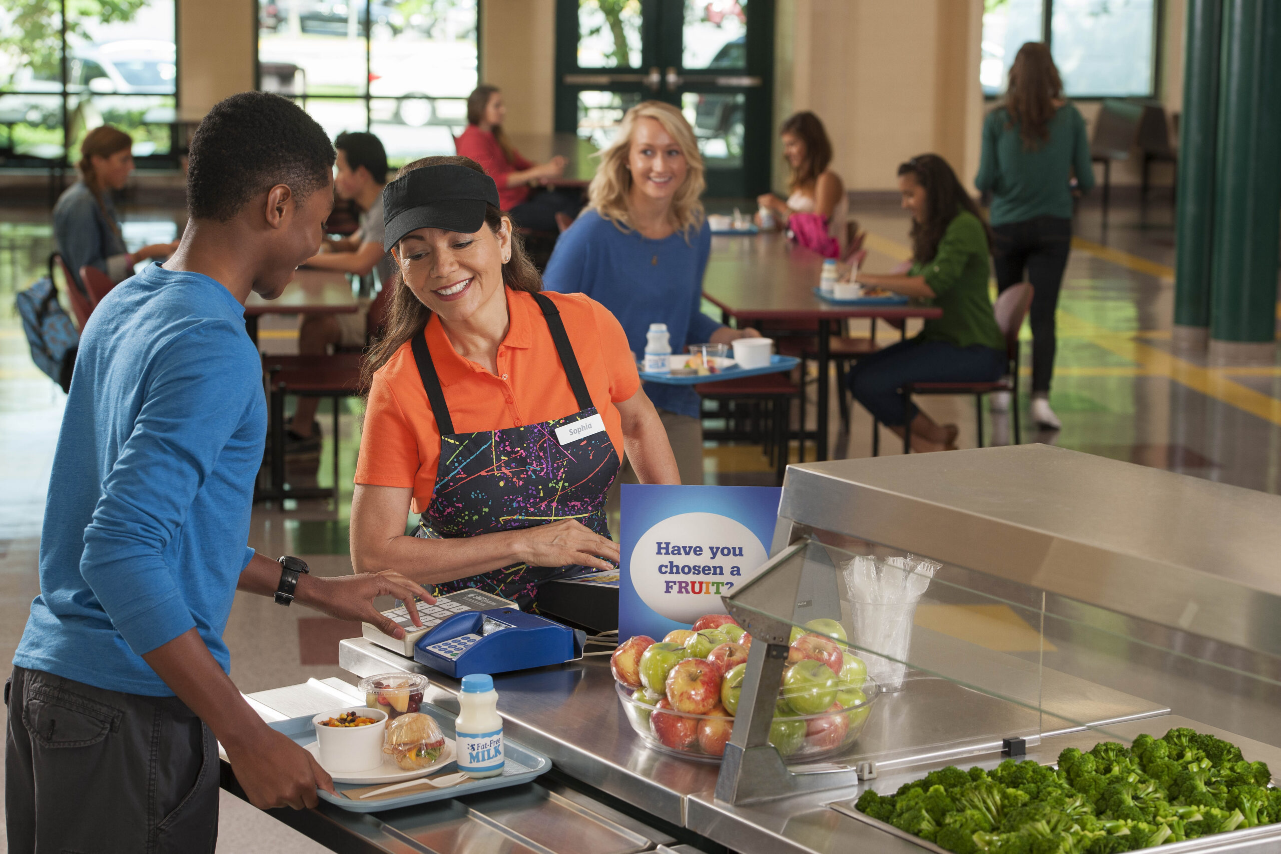 Cafeteria worker and high school student talking in cafeteria line.
