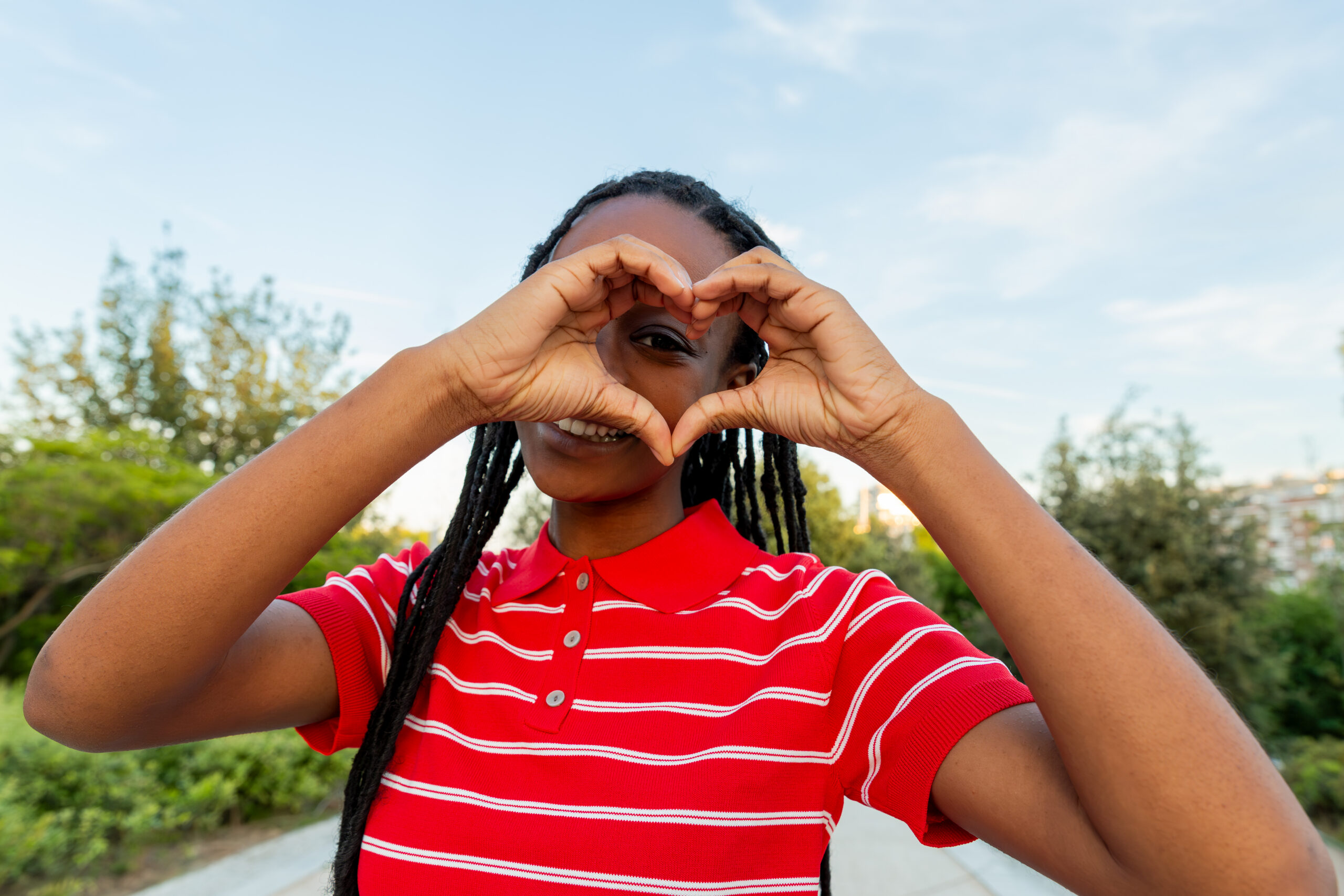 A high school student making a heart sign with her hands.
