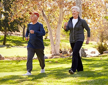 Photo showing Caucasian couple briskly walking through park