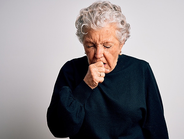 Senior woman coughing, perhaps due to COPD.