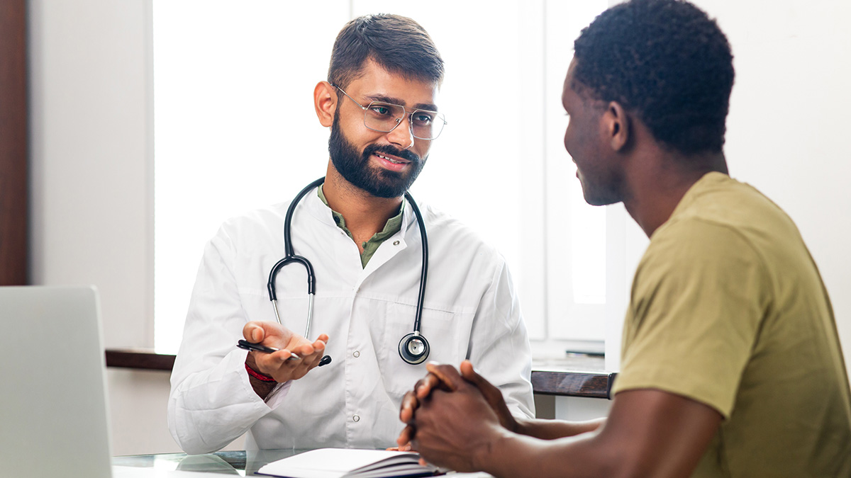 A healthcare professional speaking with a patient in his office