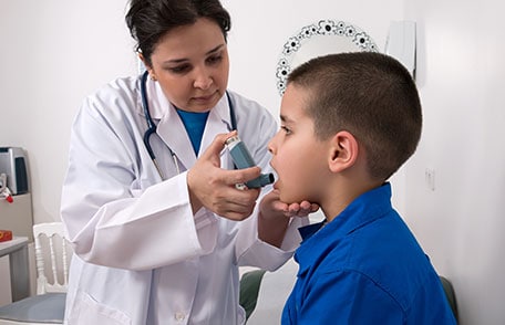 Un médico administra un inhalador para el asma a un niño.
